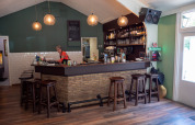Zona bar accogliente al Recreatiepark de Wrange nel Gelderland, Paesi Bassi, con sgabelli in legno e barista.
