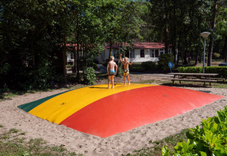 Two children play on a colorful jumping pillow at Recreatiepark de Wrange holiday park in Gelderland.