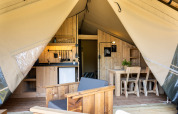 Indretning af safaritelt med køkken, spisebord og siddepladser på Camping Mareveld i Holland.