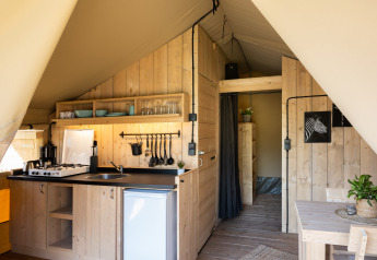 Vista interior de una tienda safari con paredes de madera, cocina, comedor y baño privado completo.