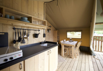 Interior de una tienda safari con cocina y comedor en Camping Mareveld, Países Bajos.