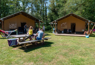 Familias disfrutando de tiendas safari con baño privado en Recreatiepark de Wrange, Países Bajos, rodeados de naturaleza.