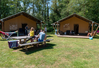 Familias disfrutando de tiendas safari con baño privado en Recreatiepark de Wrange, Países Bajos, rodeados de naturaleza.