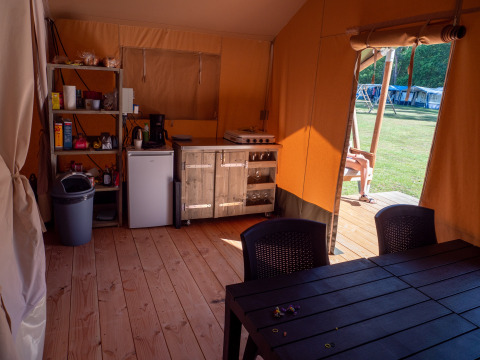 Interior de una tienda safari con cocina y mesa en Recreatiepark de Wrange, Países Bajos, con vista exterior.