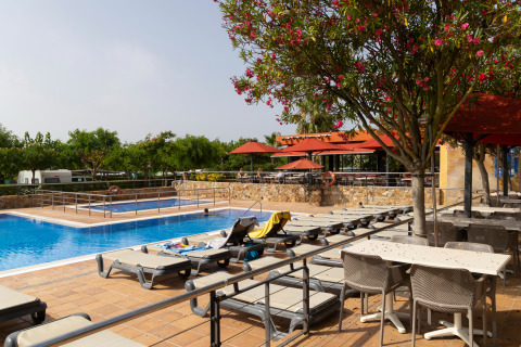Outdoor swimming pool with sun loungers and umbrellas at Camping del Mar holiday park in Catalonia, Spain.