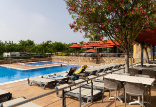 Udendørs swimmingpool med liggestole og parasoller på Camping del Mar feriepark i Catalonien, Spanien.