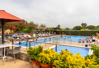 Zwembadzone met mensen en ligstoelen bij Camping del Mar, een vakantiepark in Catalonië, Spanje.