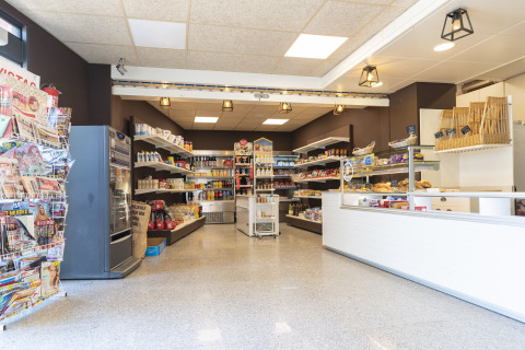 A bright supermarket at Camping del Mar, Catalonia, Spain, with shelves stocked with groceries.