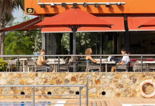 Outdoor restaurant at Camping del Mar, Catalonia, Spain, with people dining and view of swimming pool.
