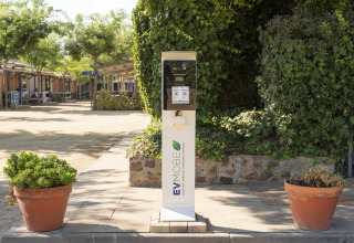 Borne de recharge pour véhicules électriques à Camping del Mar, entourée de verdure en Catalogne, Espagne.