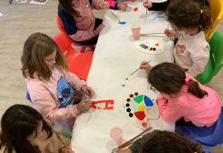 Kinderen schilderen samen rond een tafel op Camping del Mar, een vakantiepark in Catalonië, Spanje.