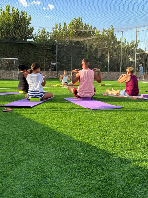 Menschen machen Outdoor-Yoga auf einer grünen Wiese bei Camping del Mar, Katalonien, Spanien, am Tag.