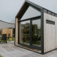 Moderne tiny house XL med træbeklædning og stor glasdør på Camping Si-Es-An i Holland, udendørs siddeplads.