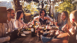 Amigos disfrutan de una comida al aire libre bajo luces en un parque vacacional con alojamiento glamping.
