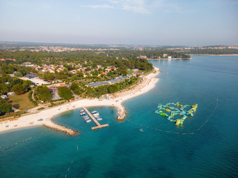 Vista aérea del parque vacacional Bi Village en Istria, Croacia, con playa, muelle y parque acuático flotante.