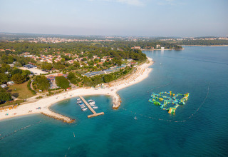 Aerial view of Bi Village holiday park in Istria, Croatia, featuring beach, pier, boats, and water playground.