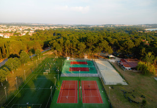 Luftfoto af sportsområder i Bi Village feriepark, Istrien, Kroatien med tennisbaner og grønne omgivelser.