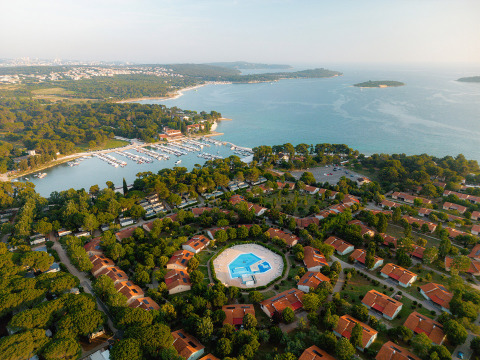 Vista aérea del parque vacacional Bi Village en Istria, Croacia, con piscina, villas y la costa al fondo.