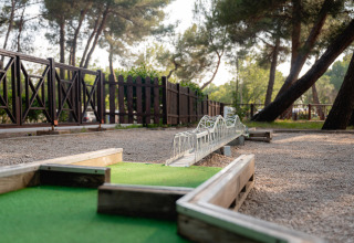 Parcours de mini-golf avec obstacle de pont dans un parc de vacances entouré d'arbres en Istrie, Croatie.