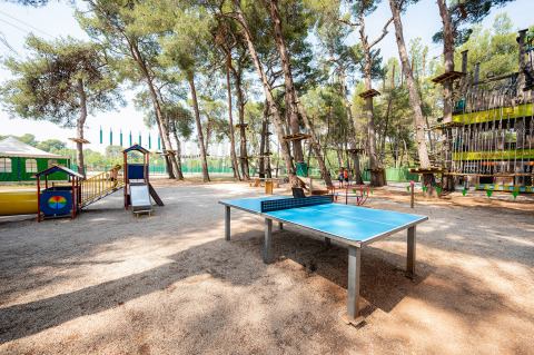 Speeltuin en tafeltennistafel in een schaduwrijk bos bij Bi Village vakantiepark in Istrië, Kroatië.