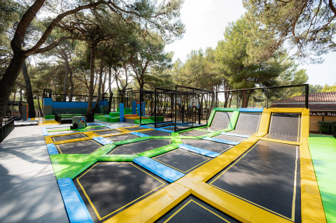 Buitentrampolinepark tussen pijnbomen bij Bi Village vakantiepark in Istrië, Kroatië, op zonnige dag.