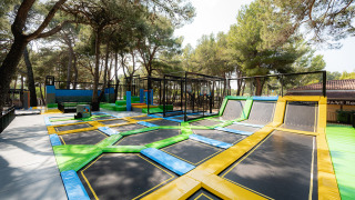 Parque de trampolines al aire libre entre pinos en Bi Village, Istria, Croacia, iluminado por el sol.