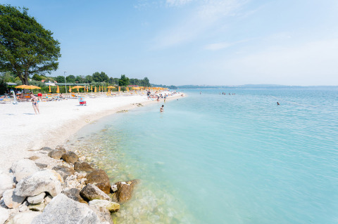 Strand met helderblauw water bij Bi Village vakantiepark in Istrië, Kroatië, met gele parasols.