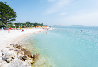 Belle plage avec eau turquoise au Bi Village, parc de vacances en Istrie, Croatie, avec des parasols jaunes.