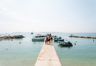 Gezin wandelt langs pier en boten in Bi Village, Istrië, Kroatië, op een zonnige en heldere dag.