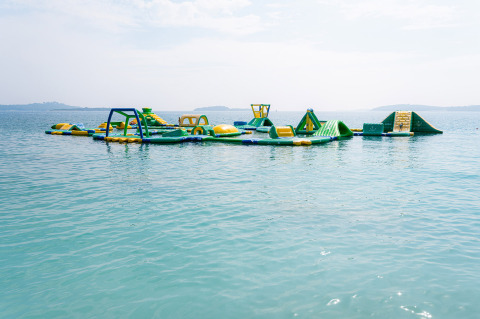 Parque acuático inflable flotando en el mar en Bi Village, parque vacacional en Istria, Croacia, al sol.