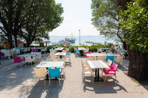 Terraza de cafetería con sillas coloridas en Bi Village, un complejo vacacional en Istria, Croacia, junto al mar.