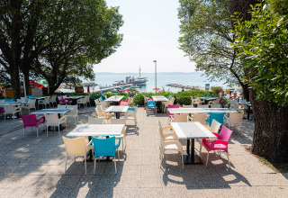 Terraza de cafetería con sillas coloridas en Bi Village, un complejo vacacional en Istria, Croacia, junto al mar.