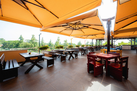 Terraza exterior con sombrillas grandes y mesas de madera en el parque vacacional Bi Village en Istria, Croacia.