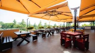 Terraza exterior con sombrillas grandes y mesas de madera en el parque vacacional Bi Village en Istria, Croacia.