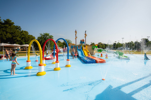 Niños jugando en un parque acuático colorido con toboganes y chorros de agua en Bi Village, Istria, Croacia.