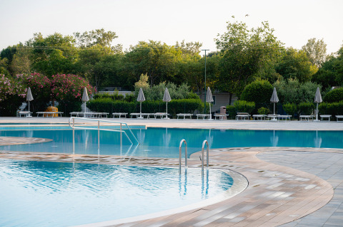 Piscina al aire libre rodeada de tumbonas y sombrillas en Bi Village, un resort en Istria, Croacia.