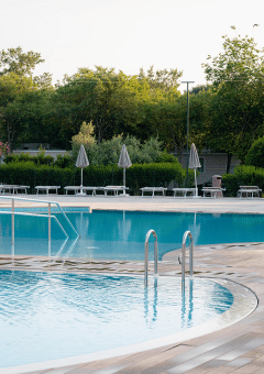 Piscina al aire libre rodeada de tumbonas y sombrillas en Bi Village, un resort en Istria, Croacia.