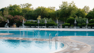 Piscina al aire libre rodeada de tumbonas y sombrillas en Bi Village, un resort en Istria, Croacia.
