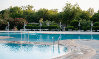 Piscina al aire libre rodeada de tumbonas y sombrillas en Bi Village, un resort en Istria, Croacia.