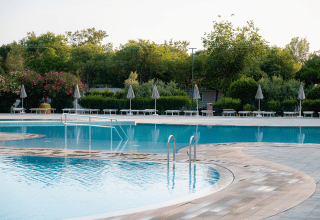 Udendørs swimmingpool omgivet af liggestole og parasoller i ferieparken Bi Village, Istrien, Kroatien.