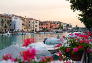 Die Wasserfront von Campeggio del Garda in Venetien, Italien, mit Booten, Blumen und bunten Häusern am Abend.