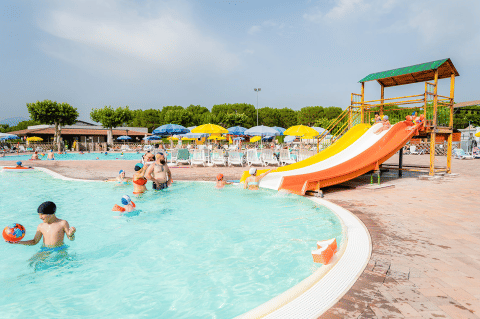 Des familles profitent de la piscine avec un toboggan et des transats à Campeggio del Garda, Vénétie, Italie.