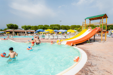 Familias disfrutan de la piscina con tobogán de agua y tumbonas en Campeggio del Garda, Véneto, Italia.