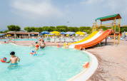 Familier nyder poolen med en vandrutsjebane og solsenge på Campeggio del Garda feriepark i Veneto, Italien.