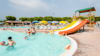 Familias disfrutan de la piscina con tobogán de agua y tumbonas en Campeggio del Garda, Véneto, Italia.