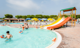 Familias disfrutan de la piscina con tobogán de agua y tumbonas en Campeggio del Garda, Véneto, Italia.