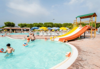 Familias disfrutan de la piscina con tobogán de agua y tumbonas en Campeggio del Garda, Véneto, Italia.