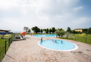 Area piscina all'aperto al Campeggio del Garda, villaggio turistico in Veneto, Italia, con bambini che nuotano.