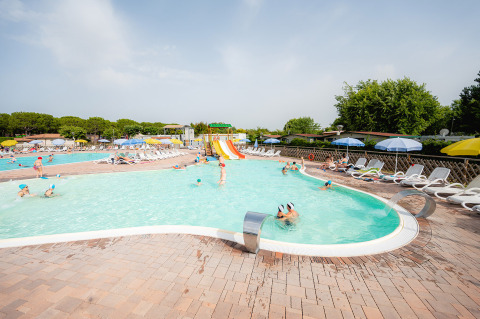 Espace piscine familial avec toboggans aquatiques, transats et parasols au Campeggio del Garda en Vénétie.