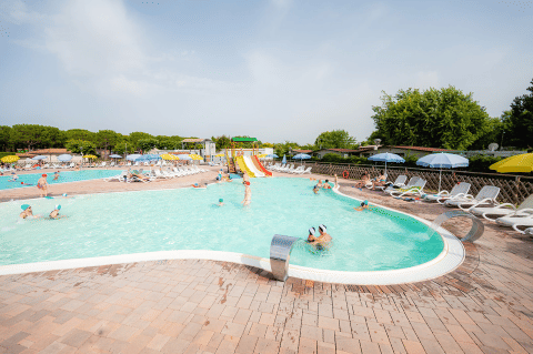 Family-friendly swimming pool area with waterslides, sun loungers and umbrellas at Campeggio del Garda in Veneto.